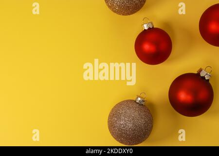Boules décoratives de Noël rouges et dorées sur fond jaune. Flat lay, vue de dessus, espace de copie Banque D'Images