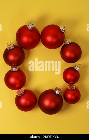 Boules décoratives de Noël rouges sur fond jaune. Flat lay, vue de dessus, espace de copie Banque D'Images