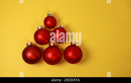 Boules décoratives de Noël rouges sur fond jaune. Flat lay, vue de dessus, espace de copie Banque D'Images