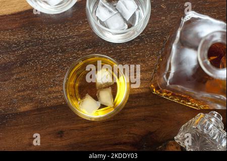 Vue en hauteur d'un verre avec chuchotement sur la glace debout le long d'un décanteur et des verres supplémentaires avec de la glace mais pas d'alcool Banque D'Images