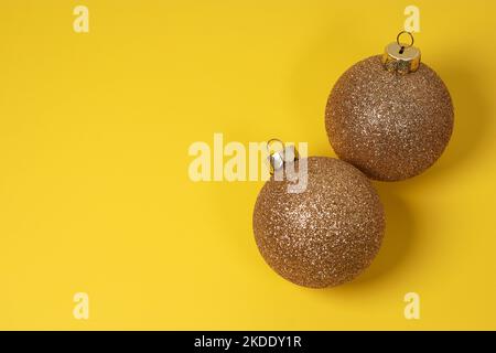 boules décoratives de Noël dorées sur fond jaune avec pin vert Banque D'Images