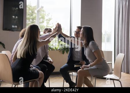 Un groupe de collègues heureux qui ont donné cinq personnes se sont réunis au bureau Banque D'Images