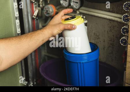 Remplacement de l'élément filtrant dans le système de purification d'eau domestique en gros plan. Vue par le portillon ouvert dans la salle de bains Banque D'Images