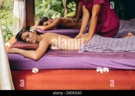 Photo d'un jeune homme et d'une jeune femme recevant un massage au centre thermal de luxe. Couple allongé sur le devant au centre de spa et ayant un massage du dos. Concentrez-vous sur la priorité Banque D'Images