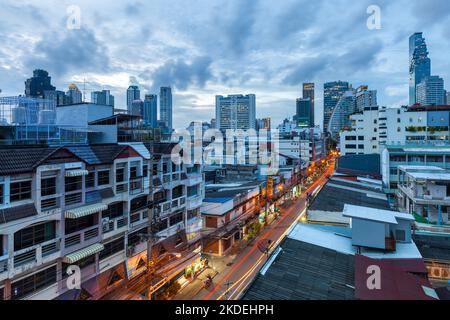 Vue au crépuscule sur la rue dans le quartier de Sathon, avec la tour du Roi Power Mahanakhon et l'hôpital Saint Louis à l'arrière-plan, Bangkok Banque D'Images