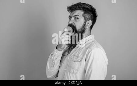 L'alimentation de l'homme mange des fruits. Concept de nutrition saine. Un bel hipster avec une longue barbe mangeant de la pomme. Hipster manger des pommes mûres juteuses Banque D'Images