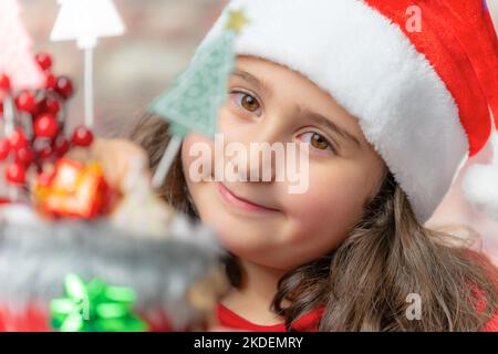 Enfant en tissu rouge de père Noël avec botte rouge de père Noël. Banque D'Images