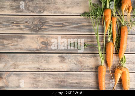 Ligne verticale de carottes fraîches mûres sur une table en bois pâle, vue du dessus. Légumes crus disposés dans l'ordre. Concept de nourriture biologique ou de régime alimentaire sain. Emplacement Banque D'Images