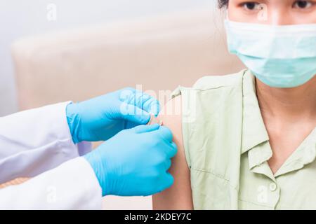 Médecin homme après injection coronavirus vaccin à la jeune femme épaule il mettant un pansement adhésif de bandage Banque D'Images