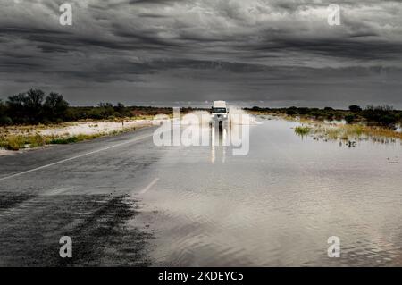 Voiture roulant sur une route inondée dans l'Outback australien. Banque D'Images