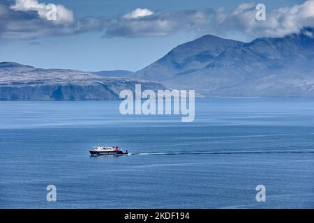 Le traversier calédonien MacBrayne Small Isles, le MV Lochnevis, quitte l'île de Canna, en Écosse, au Royaume-Uni. Les collines de Rum derrière. Banque D'Images