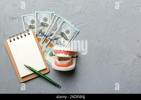 Composition de pose à plat avec modèle de typographie dentaire pédagogique et argent avec carnet sur table colorée, vue de dessus. Traitement coûteux. Banque D'Images