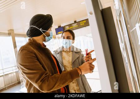 Un couple indien portant un masque facial achetant des billets à l'intérieur de l'aéroport Banque D'Images