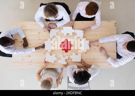 Divers membres de l'entreprise participent à l'assemblage de casse-têtes, à la coopération dans la prise de décision, au soutien de l'équipe dans la résolution des problèmes et au travail d'équipe de groupe d'entreprise Banque D'Images
