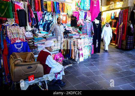 QATAR, Doha, Bazar Souq Waqif, magasin textile, travailleur migrant travaille comme porteur , aussi les gardiens de magasin sont des migrants , ils ont besoin d'un sponsor qatari pour l'entreprise / KATAR, Doha, Basar Souk Wakif, Laden mit Textilien, Träger fuer Warentransport Banque D'Images