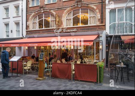 Extérieur de la rue Caffè Concerto Bond avec des personnes dînant en plein air à des tables sur la terrasse couverte. Londres, Angleterre, Royaume-Uni Banque D'Images