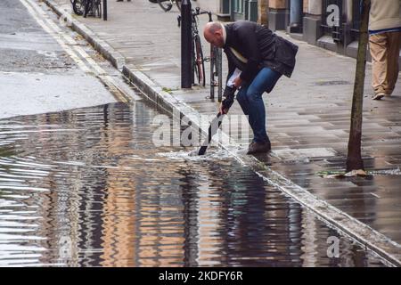 Londres, Angleterre, Royaume-Uni. 6th novembre 2022. Un homme tente de débloquer un drain dans une rue inondée de Bloomsbury, dans le centre de Londres, après de fortes pluies. (Image de crédit : © Vuk Valcic/ZUMA Press Wire) Banque D'Images