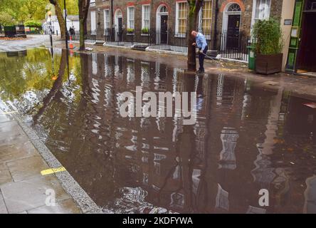 Londres, Royaume-Uni. 6th novembre 2022. Un homme tente de débloquer un drain dans une rue inondée de Bloomsbury, dans le centre de Londres, après de fortes pluies. Credit: Vuk Valcic/Alamy Live News Banque D'Images