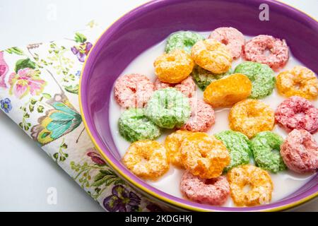 Goias, Brésil – 06 novembre 2022 : bol avec céréales de petit déjeuner colorées dans le lait, prêt à manger avec une serviette à motifs. Banque D'Images