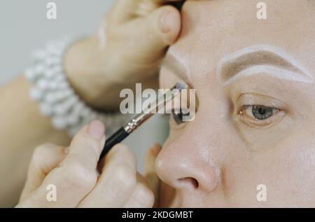 Colorier avec des lignes blanches le dessin de la forme des sourcils sur le visage d'une femme. Microblading. La beauté d'une femme. Banque D'Images