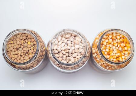 Goias, Brésil – 06 novembre 2022 : haricots, cornes et lentilles à l'intérieur de pots en verre sur une surface de couleur blanche. Banque D'Images