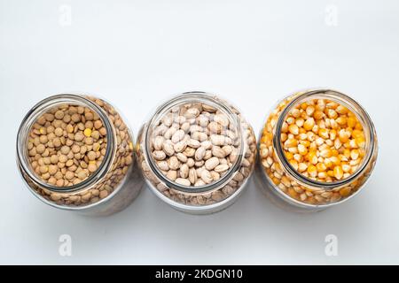 Goias, Brésil – 06 novembre 2022 : haricots, cornes et lentilles à l'intérieur de pots en verre sur une surface de couleur blanche. Banque D'Images