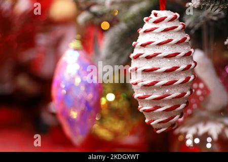Jouets de Noël en forme de cône de pin sur fond de fête flou. Arbre du nouvel an avec décorations Banque D'Images
