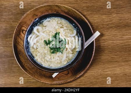 Le miso Ramen nouilles asiatiques avec l'oeuf et le persil dans le bol en bois rustique marron sur l'arrière-plan. Banque D'Images
