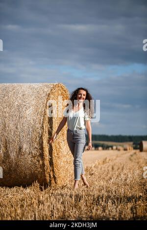 Belle fille près des balles de foin dans la campagne. Fille sur le fond de haystacks Banque D'Images