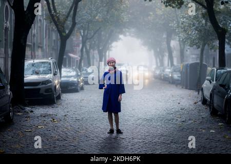 Une femme se tient dans une cour résidentielle dans un brouillard dense. Banque D'Images