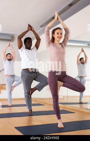 Groupe de personnes pratiquant la pose d'arbre dans la salle de gym Banque D'Images