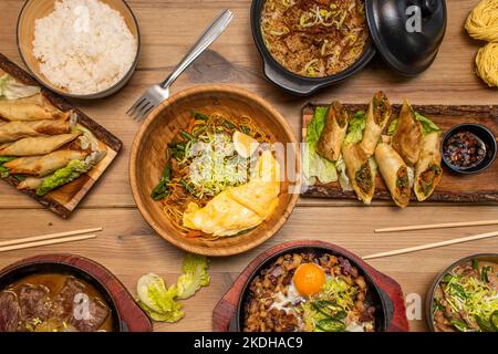 Ensemble de plats asiatiques vietnamiens avec nouilles, omelettes, petits pains farcis aux crevettes, riz sauté, légumes sautés et rôti de bœuf dans de la soupe miso Banque D'Images