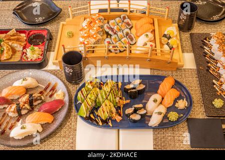 Ensemble de plats de fruits de mer, sushi de toutes sortes, gyozas japonais, riz et algues nori, saumon norvégien et thon almadraba et verres avec saké Banque D'Images