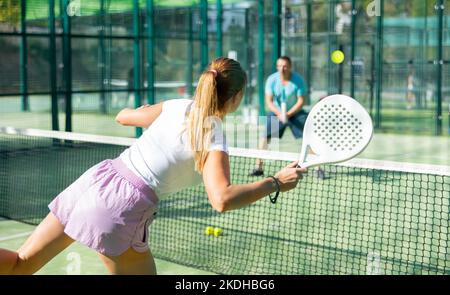 Femme sportive mince avec raquette jouant au padel sur le court. Vue de l'arrière Banque D'Images