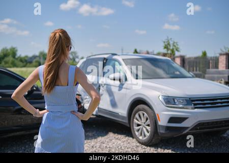 Femme stressée conducteur debout sur le côté de la rue choqué après un accident de voiture. Concept de sécurité routière et d'assurance Banque D'Images