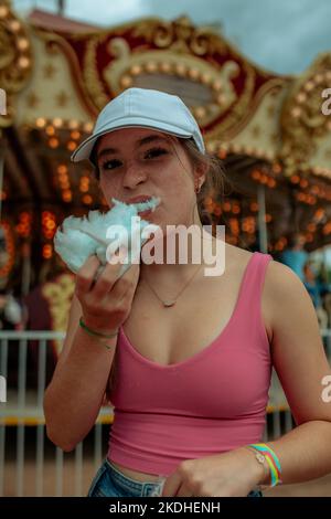 Jeune fille mangeant des bonbons de coton à un carnaval Banque D'Images