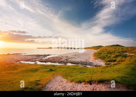 Pointe extrême nord-ouest de l'Écosse. Lumière du soleil spectaculaire et chaude de fin de coucher de soleil illuminant sur les sables fins et les dunes herbeuses, nuages wispy et bleu, ciel orange Banque D'Images