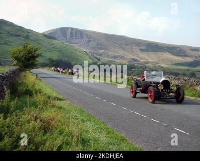 Un couple conduit une voiture ancienne à Castleton dans le parc national de Peak District, Derbyshire Angleterre Royaume-Uni 1928 Bentley 3 litres, les enfants de l'école marchent sur la route Banque D'Images