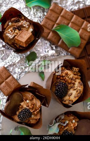 Muffin aux feuilles de mûre et d'eucalyptus sur papier d'aluminium argenté.dessert au chocolat. Table sucrée assortie. Bonbons et desserts. Produits de boulangerie et desserts Banque D'Images