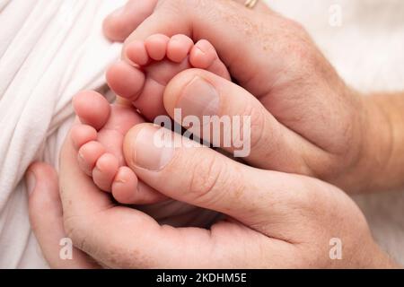 La mère fait un massage sur son pied de bébé. Gros plan des pieds de bébé dans les mains de la mère. Banque D'Images