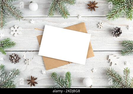 Carte de vœux de Noël dans un cadre en sapin, décorations de vacances sur fond blanc en bois. Maquette. Pose à plat. Vue de dessus Banque D'Images