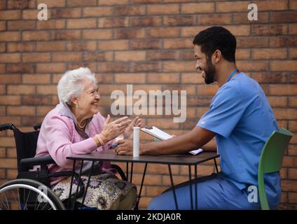 Aide-soignant expliquant la prise de pilules à une femme âgée. Banque D'Images