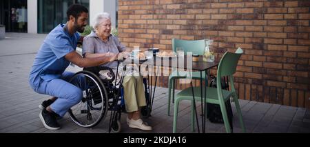 Soignant prenant le petit déjeuner avec son client au café. Banque D'Images