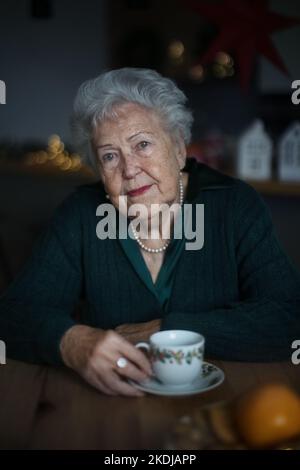 Femme âgée malheureuse assise seule et attendant sa famille pendant la veille de Noël.concept de solitude, de santé mentale et de sénior. Banque D'Images
