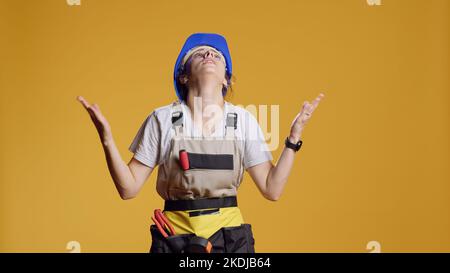Portrait d'un ouvrier de construction faisant des mains de prière geste, souhaitant terminer les travaux de rénovation. Être régalieux et prier à dieu d'espérer la bonne chance, ayant foi en studio. Banque D'Images