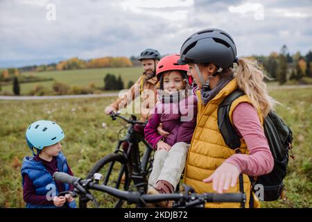 Une jeune famille avec de petits enfants se préparant à une balade à vélo dans la nature. Concept de mode de vie sain. Banque D'Images