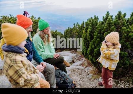 Petite fille prenant des photos de sa famille, ayant fait une pause pendant la randonnée en montagne. Banque D'Images