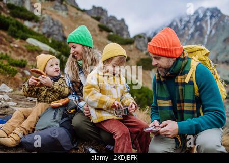 Une famille heureuse se reposer, prendre un en-cas pendant la randonnée dans les montagnes d'automne. Banque D'Images