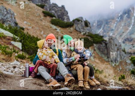 Bonne famille assise et repos, pendant la randonnée ensemble dans les montagnes d'automne. Banque D'Images