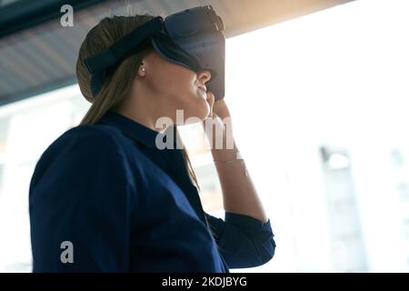 La réalité virtuelle n'est plus qu'un rêve : une jeune femme d'affaires portant un casque VR dans un bureau. Banque D'Images
